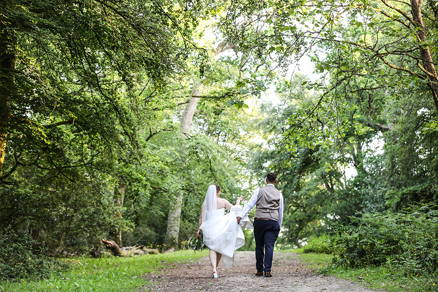 Bride and groom walking through woodland at Bartley Lodge in the New Forest.