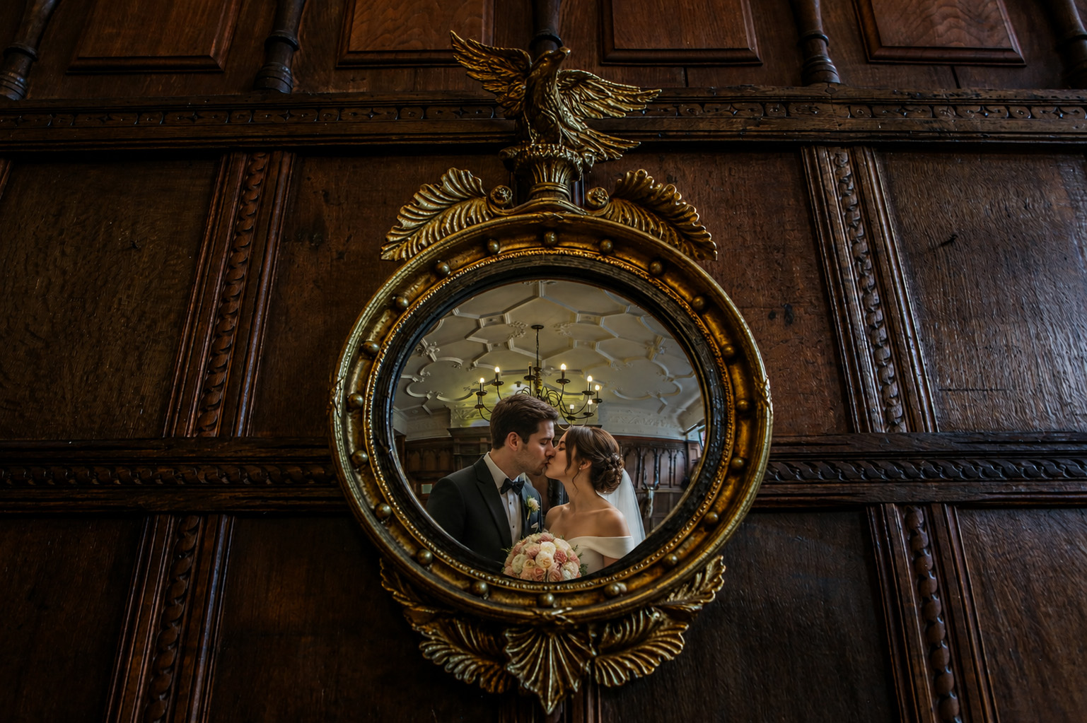 Bride and groom reflected in an ornate antique mirror inside Efford Park Manor during their Hampshire wedding celebration.