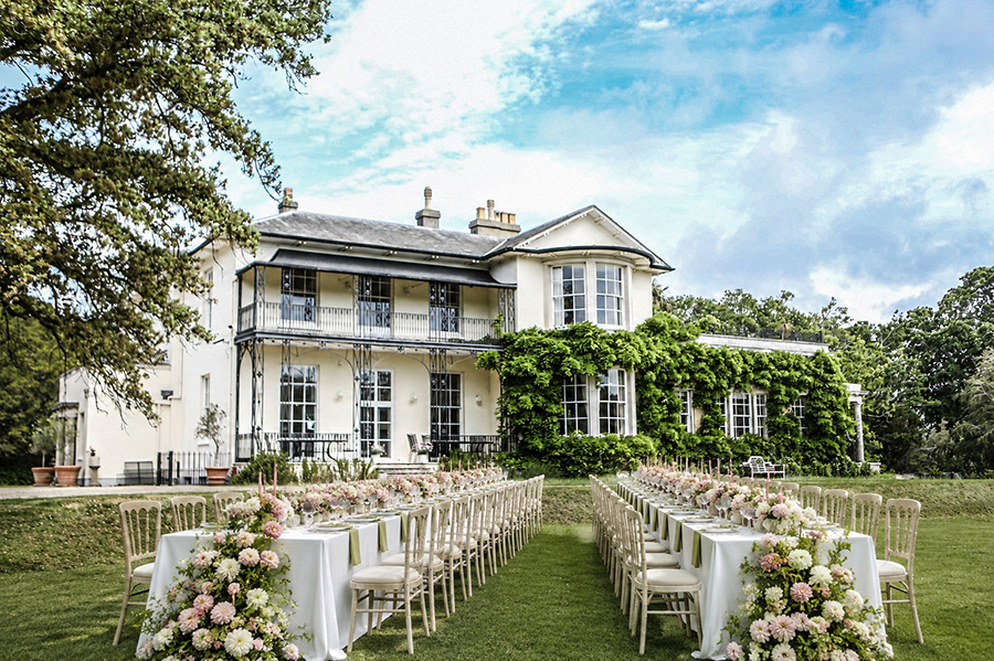 Outdoor wedding ceremony setup in front of a luxury Hampshire country house wedding venue with aisle, floral displays and guest seating.